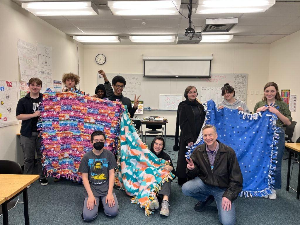 7 students and one teacher holding tie blankets that they made